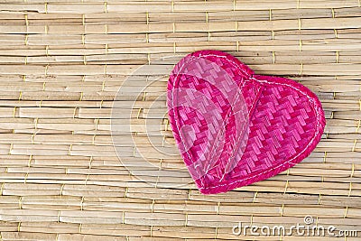 Pink bamboo wood heart on reed texture background, love and romance symbol Stock Photo