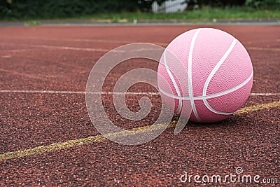 Pink basketball ball on the ground. Close-up ball on the red court. Stock Photo