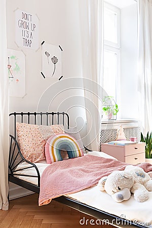 Pink bedding and teddy bear on small kids bed Stock Photo