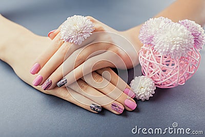 Pink and black manicure on female hands with flowers on grey background. Nail art and design Stock Photo