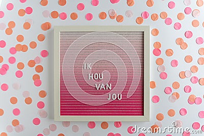 Pink Board Words That Spell Ik Hou Van Jou (translation: I love you), on a white background with confetti Stock Photo