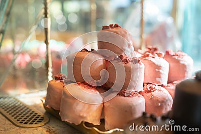 Pink cakes pyramid on counter. Sweet strawberry cherry mousse mini cupcakes with sprinkles on top Stock Photo