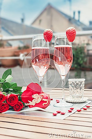 Pink champagne in two glasses, heart shaped french macaron and roses on a balcony table. Romantic, love or Valentine`s day concept Stock Photo