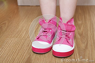 Pink children shoes on standing floor legs Stock Photo