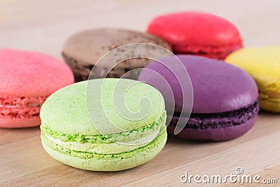 Pink, coffee, red, green, purple and yellow cake macaroni lie on a light wooden table Stock Photo