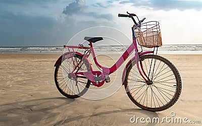 Pink colored old ladies bicycle parked on beach after cycling. A fun filled healthy activity and must to do on beach Stock Photo