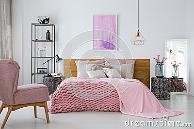 Pink woolen blanket and duvet on warm king size bed in classy bedroom interior, abstract painting on empty wall Stock Photo