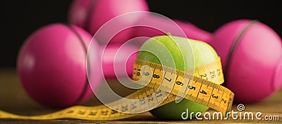 Pink dumbbells with green apple and measuring tape Stock Photo