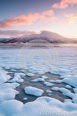 Pink early morning glow light on snow covered mountains in arctic norway, super wide panoramic scene. Scenic winter view Stock Photo