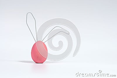 Pink Easter egg with ears made of wire. The concept of the Easter Bunny. White isolated background with soft shadow Stock Photo