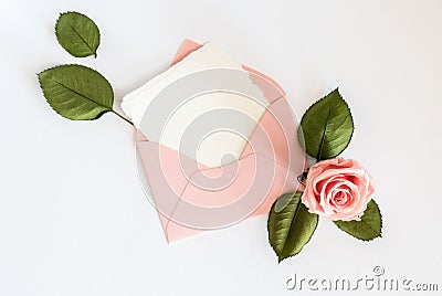 Pink envelop with white card and rose. Flat lay. Stock Photo