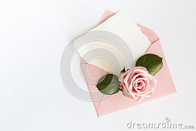 Pink envelop with white card and rose. Flat lay. Stock Photo