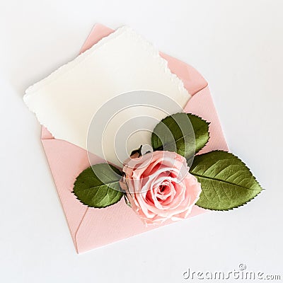 Pink envelop with white card and rose. Flat lay. Stock Photo