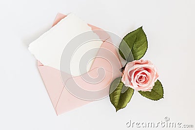 Pink envelop with white card and rose. Flat lay. Stock Photo