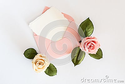 Pink envelop with white card and roses. Flat lay. Stock Photo