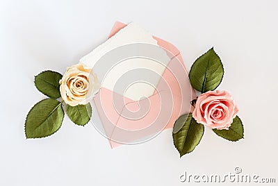 Pink envelop with white card and roses. Flat lay. Stock Photo