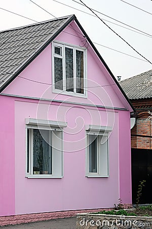 Pink facade of a one-story house with a triangular roof. Stock Photo