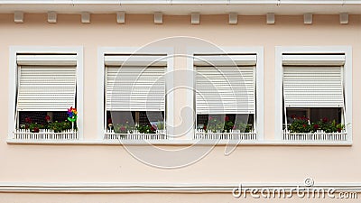 Pink facade with windows decorated with flowers Stock Photo