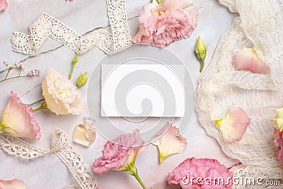 Pink flowers and a blank card laying on a marble table Stock Photo