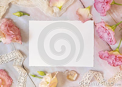 Pink flowers and a blank invitation card laying on a marble table Stock Photo