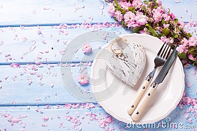 Pink flowers, heart, knife and fork on white plate on blue w Stock Photo