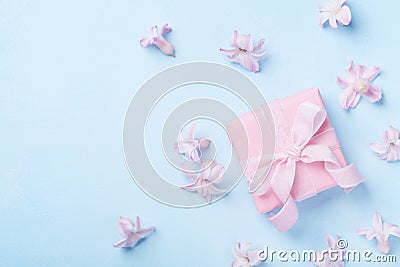 Pink flowers and present or gift box on blue pastel table top view. Greeting card for 8 March, Womans or Mothers Day. Flat lay. Stock Photo