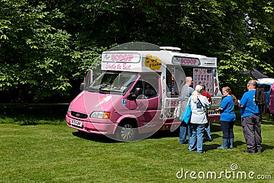 Pink Ford Transit van in a green park providing ice cream to customers in a queue Editorial Stock Photo