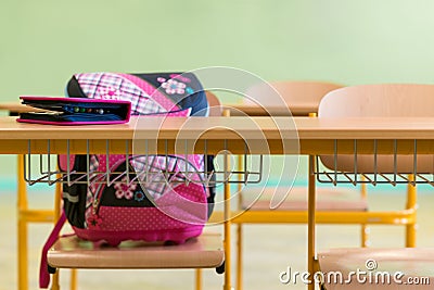 Pink girly school bag and pencil case on a desk in an empty classroom. First day of school. Stock Photo