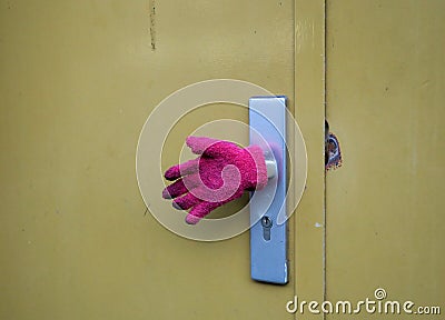 Pink glove covering a door handle of an ocre colored door of a c Stock Photo