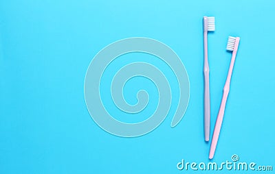 Pink and gray toothbrushes on blue background. Taking care of teeth, dental concept. Flat lay photo, copy space, top view Stock Photo