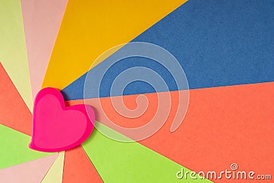 Pink heart on colored paper in the form of rays depart from the left edge Stock Photo