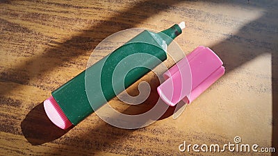 Pink highlighter on the wooden table with sunrays falling in it with shadows..Space for text also Stock Photo