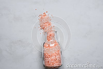 Pink Himalayan Salt in Vintage Glass Bottle Spilled on Grey Stone Tabletop. Wellness Spa Healthy Diet Nutrition Ayurveda Concept Stock Photo
