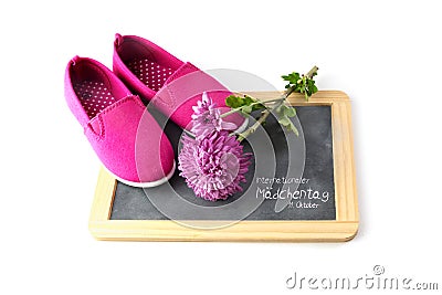 Pink kid shoes and a flower on a writing blackboard isolated on Stock Photo