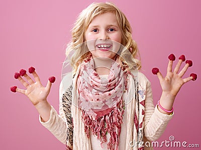 Happy girl on pink background showing raspberries on fingers Stock Photo