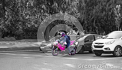 Pink motorcyclist standing out among balck and white cars Editorial Stock Photo