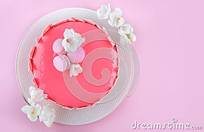 Pink mousse cake with mirror glaze decorated with macaroons, flowers for Happy Birthday on pink holiday background Stock Photo