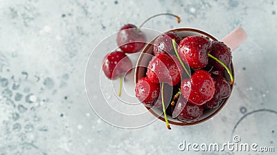 Pink mug with fresh ripe cherries. Sweet organic berries on a light concrete background. Top view with copy space Stock Photo