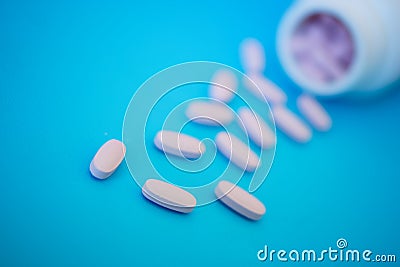 Pink oblong tablets spilled on a blue background. Medicine and health. Shallow depth of field Stock Photo