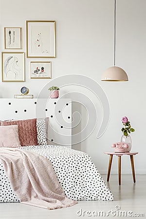 Pink, old-fashioned phone on a wooden side table and a pendant l Stock Photo