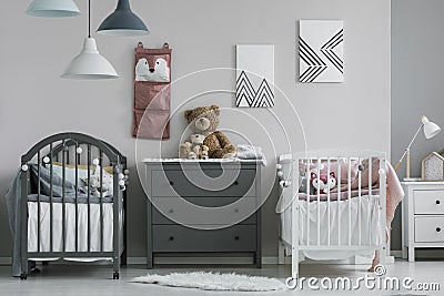 Organizer on wall of trendy baby bedroom with two cribs and chest of drawers Stock Photo