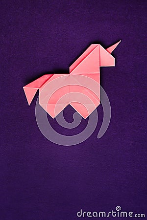 Pink origami unicorn on dark ultra violet background Stock Photo