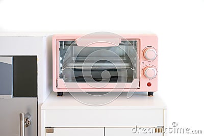 Pink pastel colour of Microwave, a modern kitchen appliance toys for kids to make up table settled in a white playroom Stock Photo