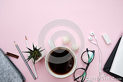 Pink pastel table with accessories notebook, phone, sheet, pencils, candy, coffee, pencils on pink background. Top view Stock Photo