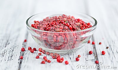 Pink Peppercorns on wooden background; selective focus Stock Photo