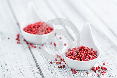 Pink Peppercorns on wooden background; selective focus Stock Photo