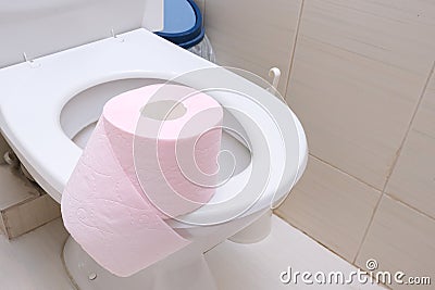 A pink piece of toilet paper standing on a seat of a toilet bowl, digestive problems and defecation disorder concept Stock Photo
