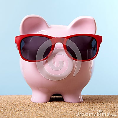 Pink piggy bank beach sunglasses sand travel money saving Stock Photo