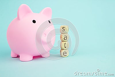 Pink piggy bank with geometric wood blocks cube adt text SALE on blue background. Saving money for sales of the year, black friday Stock Photo