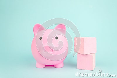 Pink piggy bank with geometric wood blocks cube on blue background Stock Photo
